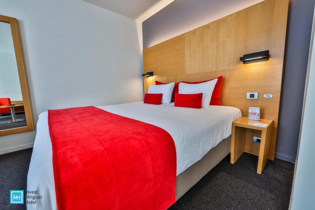 列日酷洛内列日酒店的酒店客房配有一张带红色枕头的大床