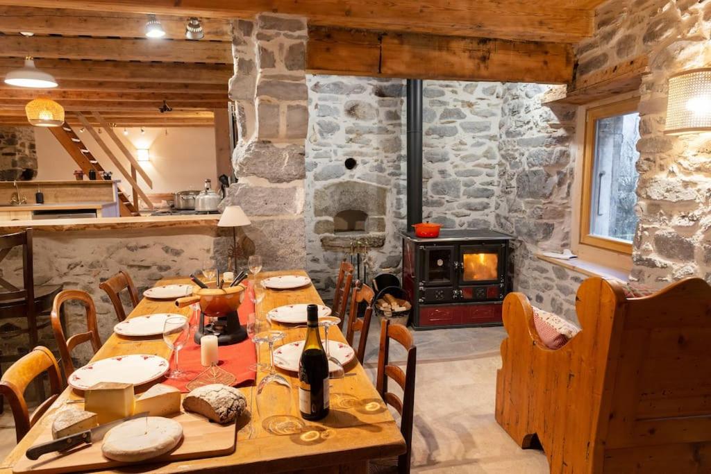 西克斯特Gîte ferme en permaculture avec ses animaux的一间带桌子和石头壁炉的用餐室