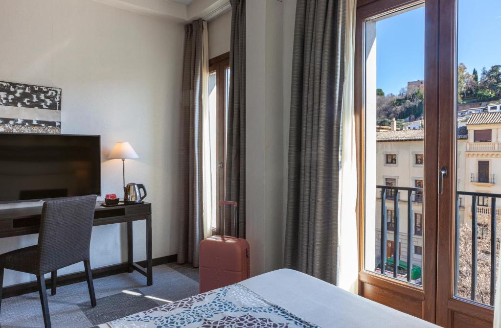 格拉纳达Hotel Macià Plaza的配有一张床、一张书桌和一扇窗户的酒店客房