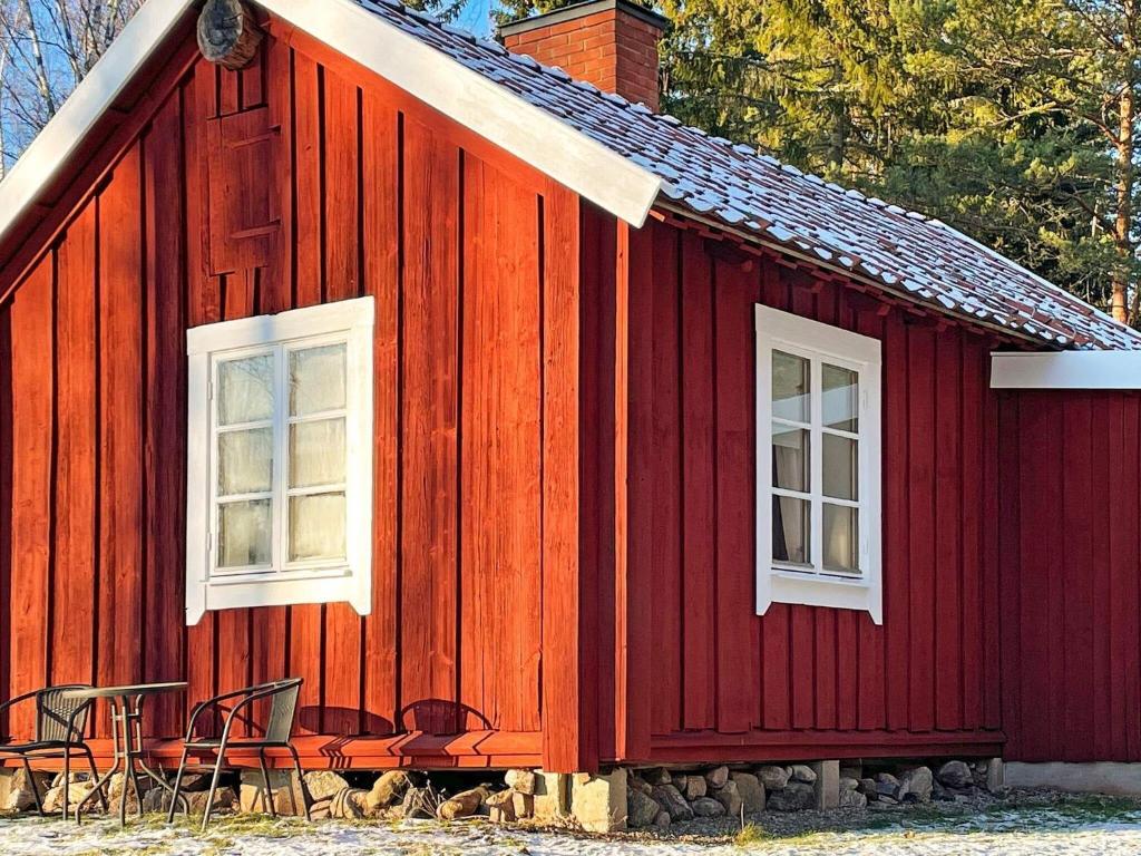 MalmköpingHoliday home ESKILSTUNA V的红色的房子,外面有两扇窗户和椅子