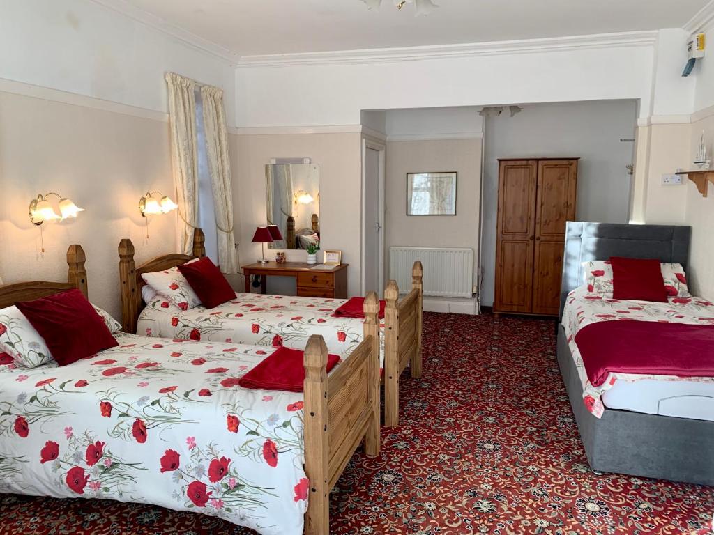 斯凯格内斯Knighton Lodge的一间卧室配有两张红色和白色床单