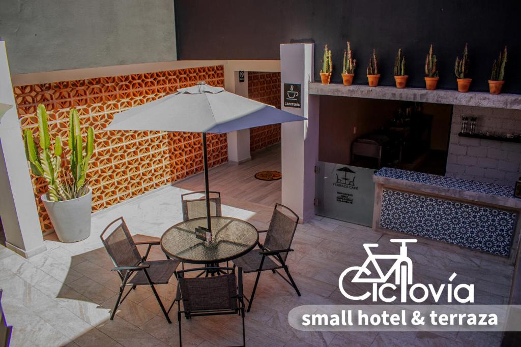 ZitácuaroHotel Ciclovía & Terraza的庭院配有桌椅和遮阳伞。