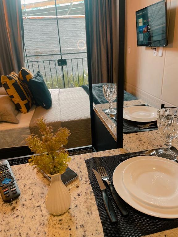 巴拉奈里奥-坎布里乌LOFT BC的一间酒店客房,配有一张带盘子的桌子,另一间则配有一张床