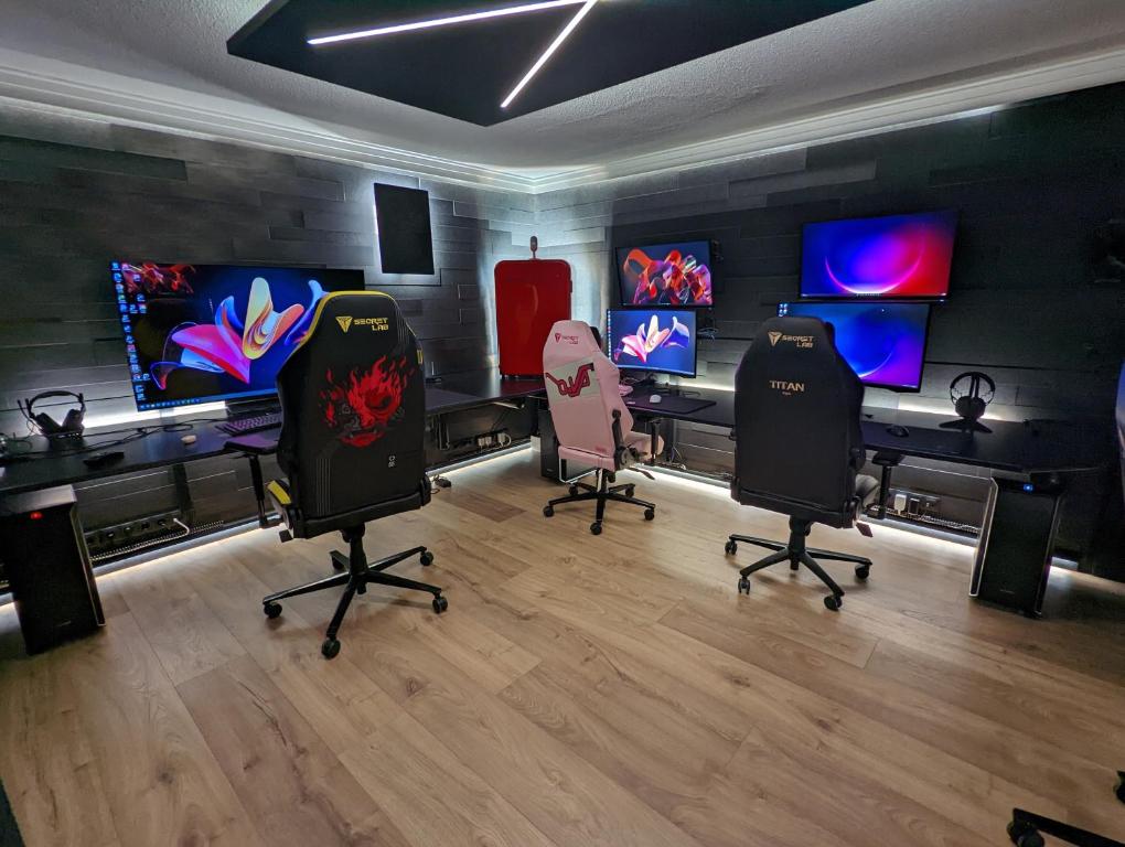 凯夫拉维克Smart Luxury - Gaming Arena, Gym, Sauna and Jacuzzi的一个房间,有3台电脑显示器和3把椅子