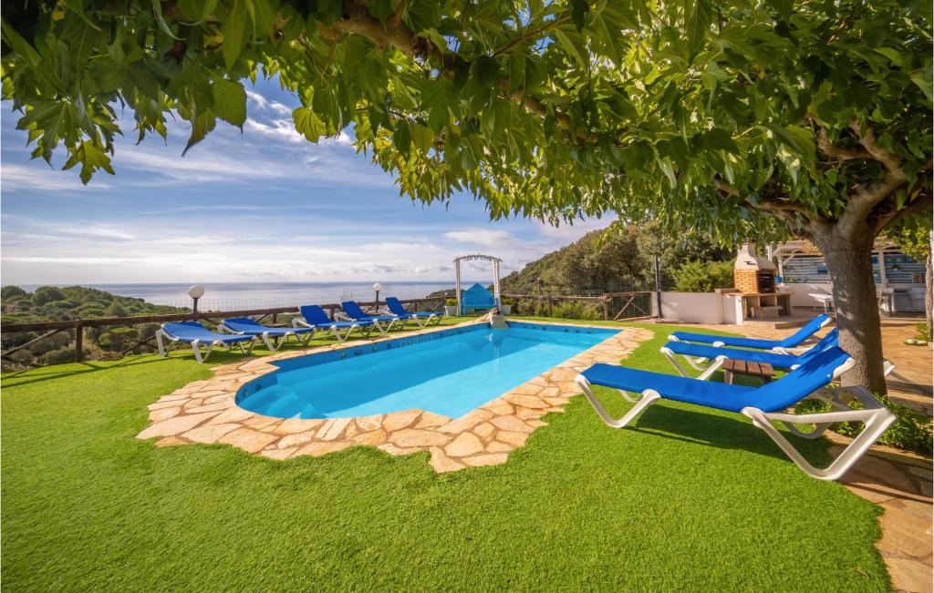 马尔格莱特德玛Lovely Home In Malgrat De Mar With Swimming Pool的一个带椅子和树的游泳池