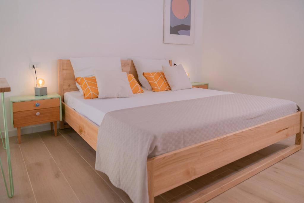 Soverato SuperioreTiny house in the historic centre of Soverato的一间卧室配有带橙色和白色枕头的木床