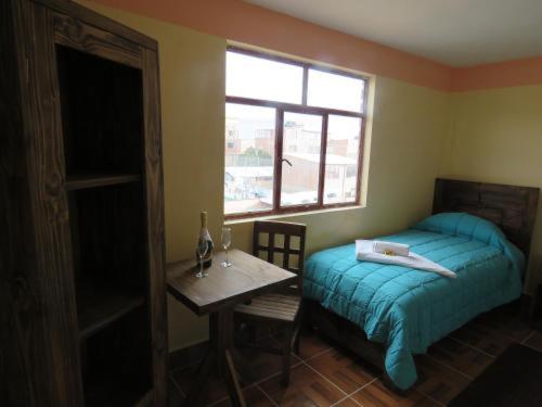 乌尤尼Beliz Inn的一间卧室配有一张床、一张桌子和一个窗户。