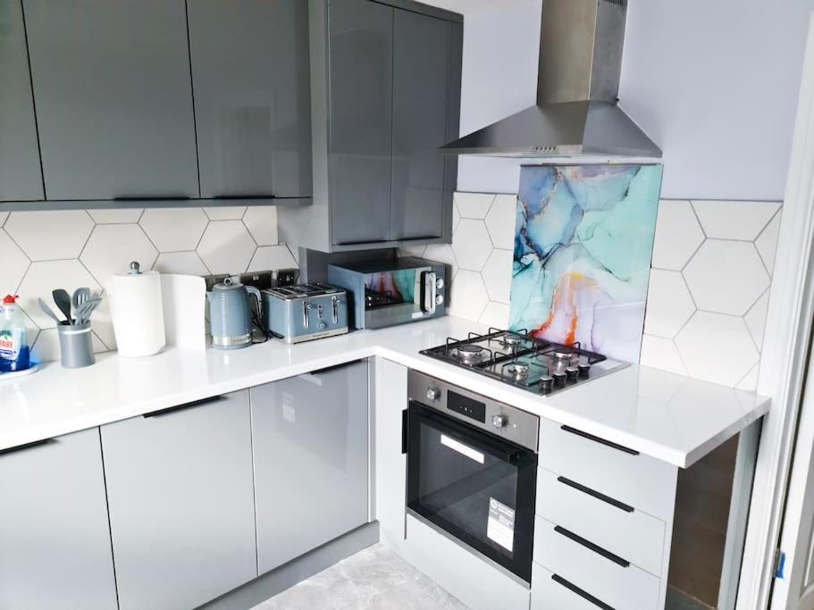 伦敦The Navarone Blue Orchid Flat的厨房配有白色橱柜和炉灶烤箱。