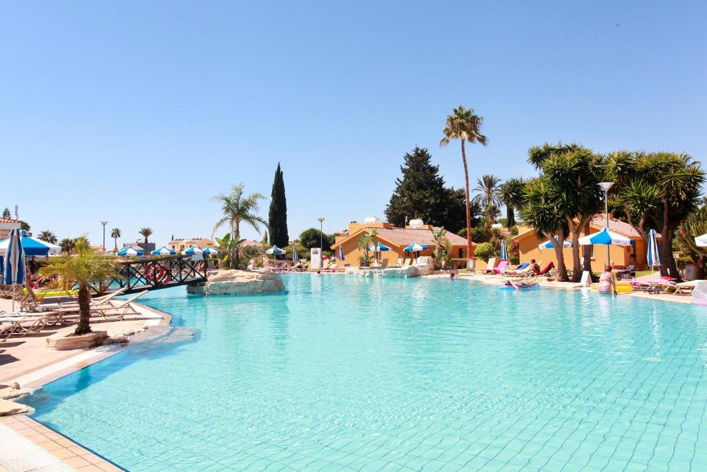 阿依纳帕马克罗尼索斯岛村公寓式酒店的棕榈树度假村内的大型游泳池