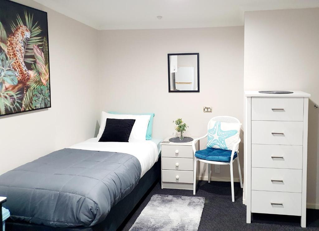 但尼丁Extended Stay City Hostel的一间卧室配有一张床、梳妆台和椅子