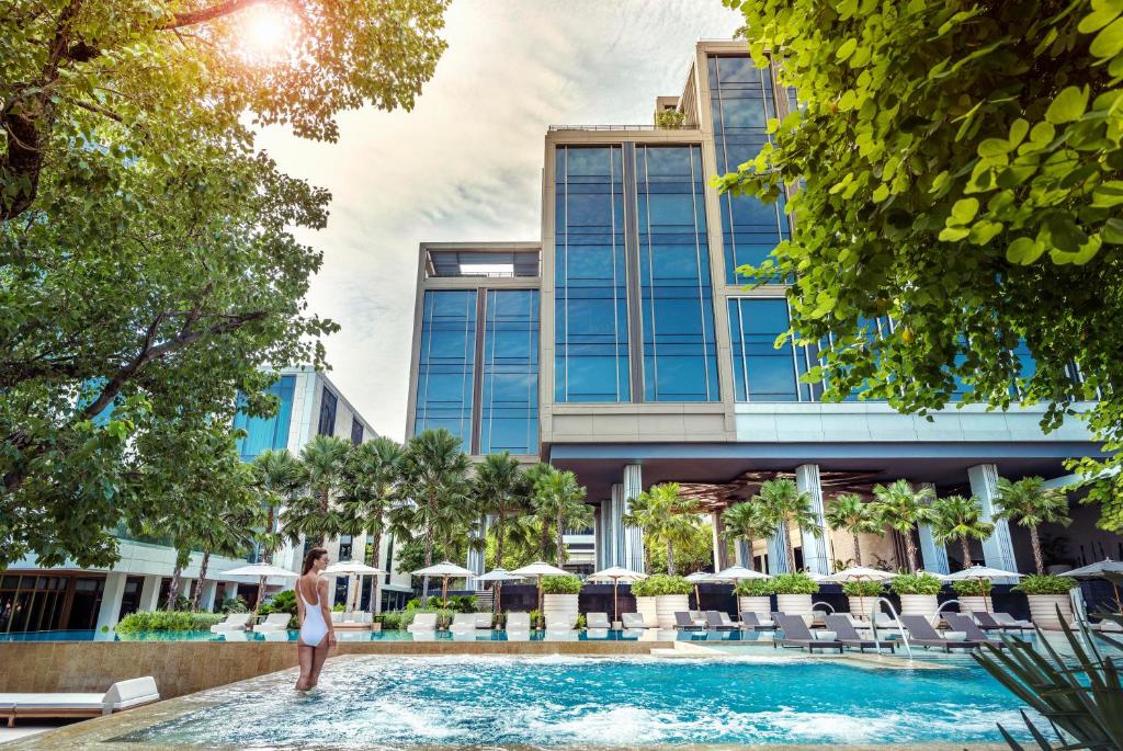 曼谷四季酒店 曼谷湄南河四季酒店的站在酒店游泳池中的女人的 ⁇ 染