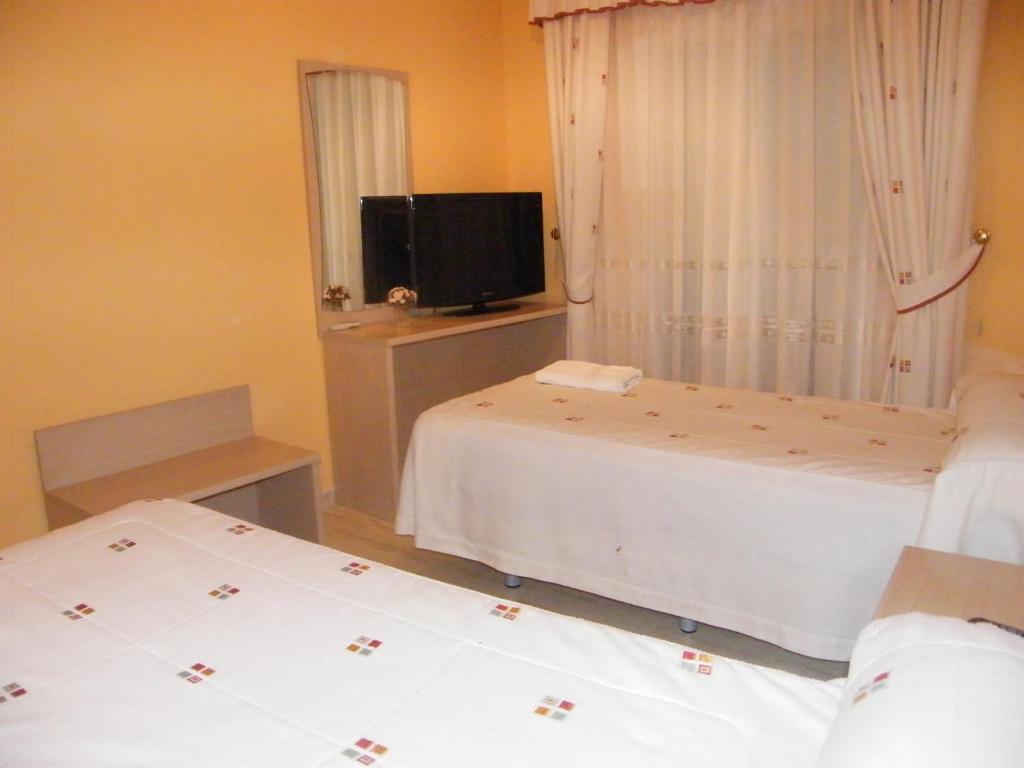 埃斯基维亚斯杜尔西内亚旅馆的一间卧室设有两张床、一台电视和一扇窗户。