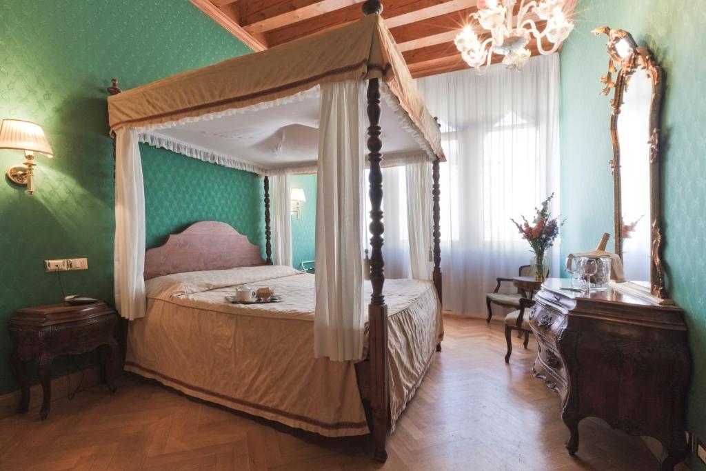 威尼斯帕拉索香东皮亚诺安蒂科酒店的一间卧室设有天蓬床和绿色的墙壁