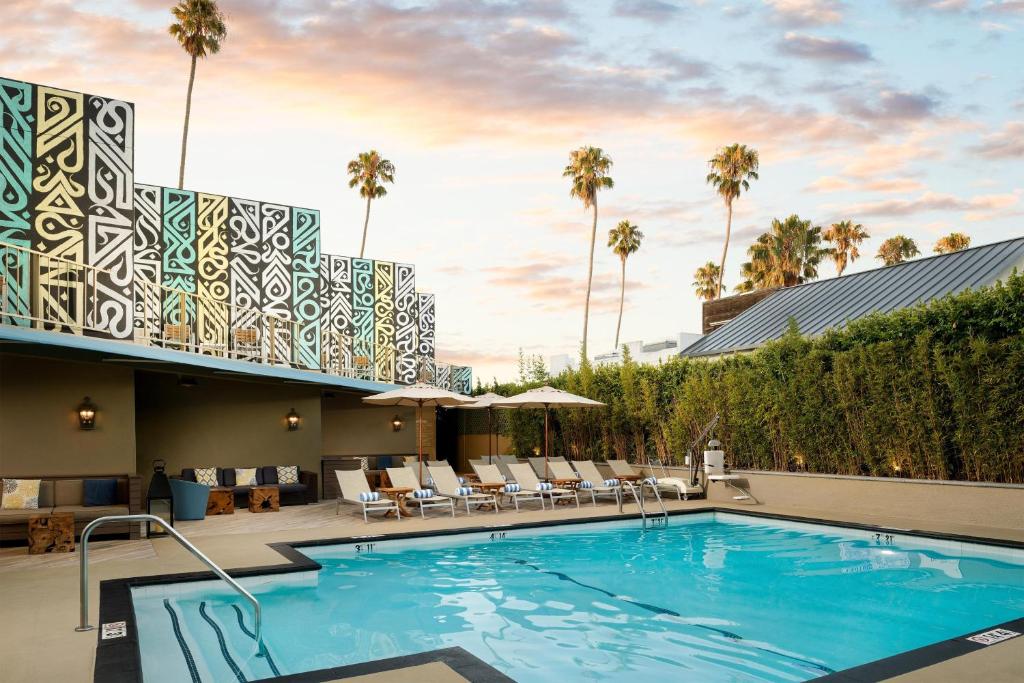 洛杉矶艾美德尔菲娜圣莫尼卡酒店的棕榈树酒店后方的游泳池