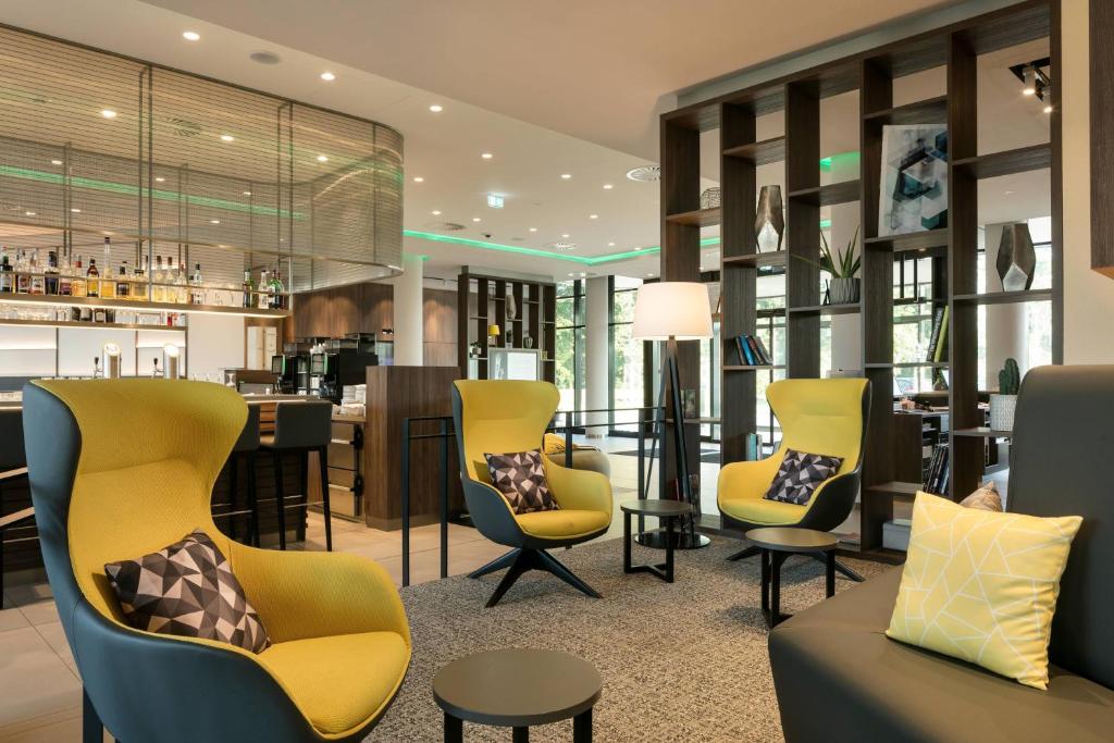 沃尔夫斯堡沃尔夫斯堡万怡酒店的大堂设有黄色椅子和酒吧
