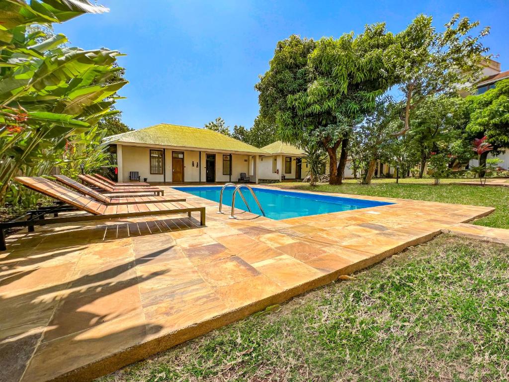 莫希Bristol Cottages Kilimanjaro的一个带游泳池和房子的后院