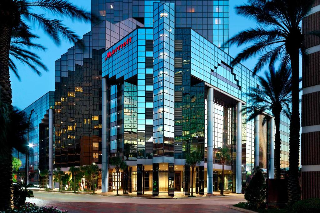 梅泰里新奥尔良梅泰里莱克威万豪酒店的一座高大的玻璃建筑,前面有棕榈树