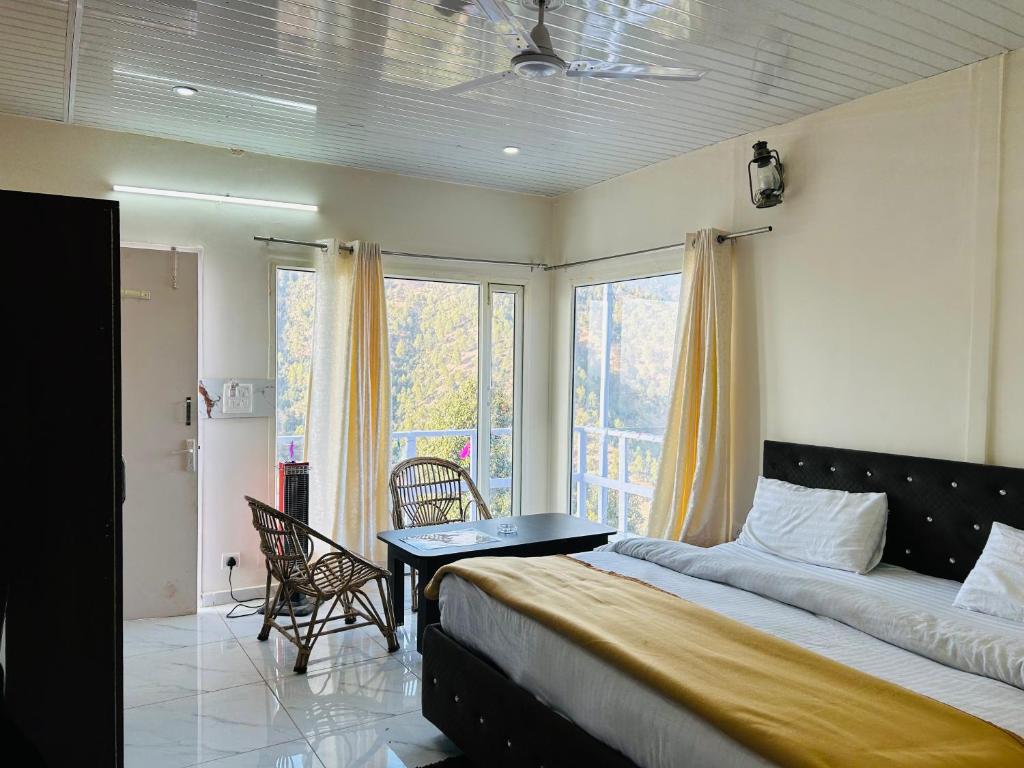 卡纳塔尔IN APPLE ESTATE KANATAL - Himalayan View Resort with Courteous Staff的一间卧室配有一张床、一张桌子和一个窗户。