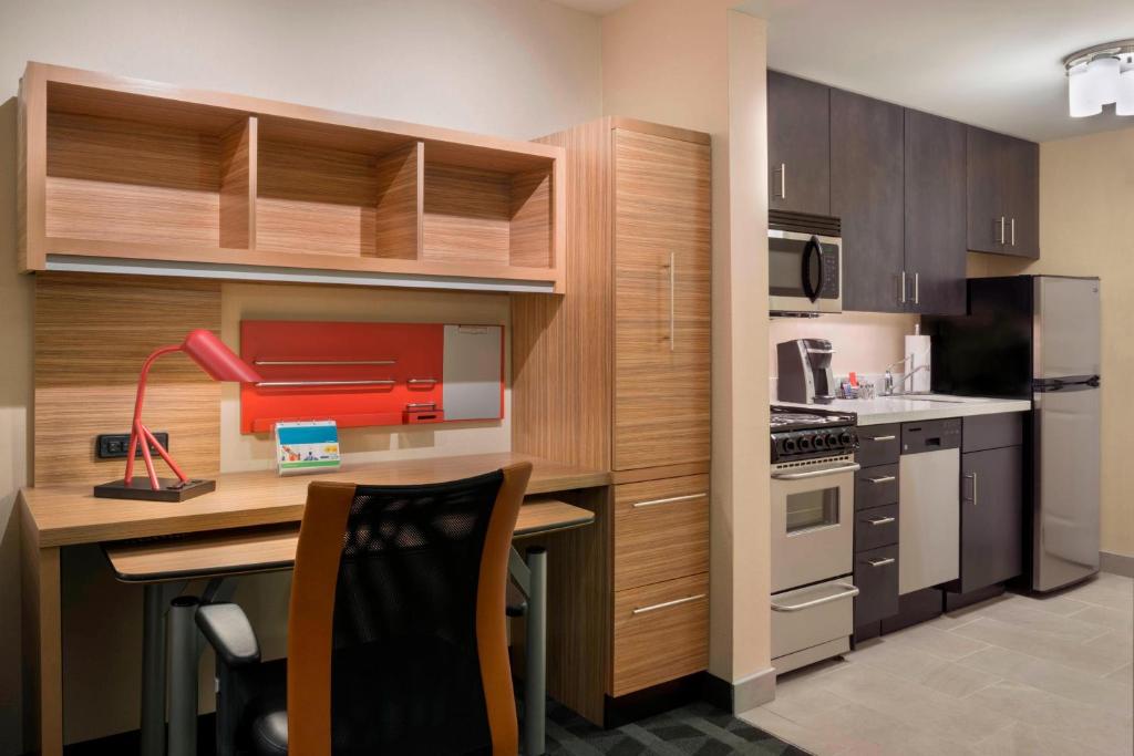 渥太华渥太华喀拉塔万豪广场套房酒店的厨房配有木制橱柜和带红色打印机的书桌。
