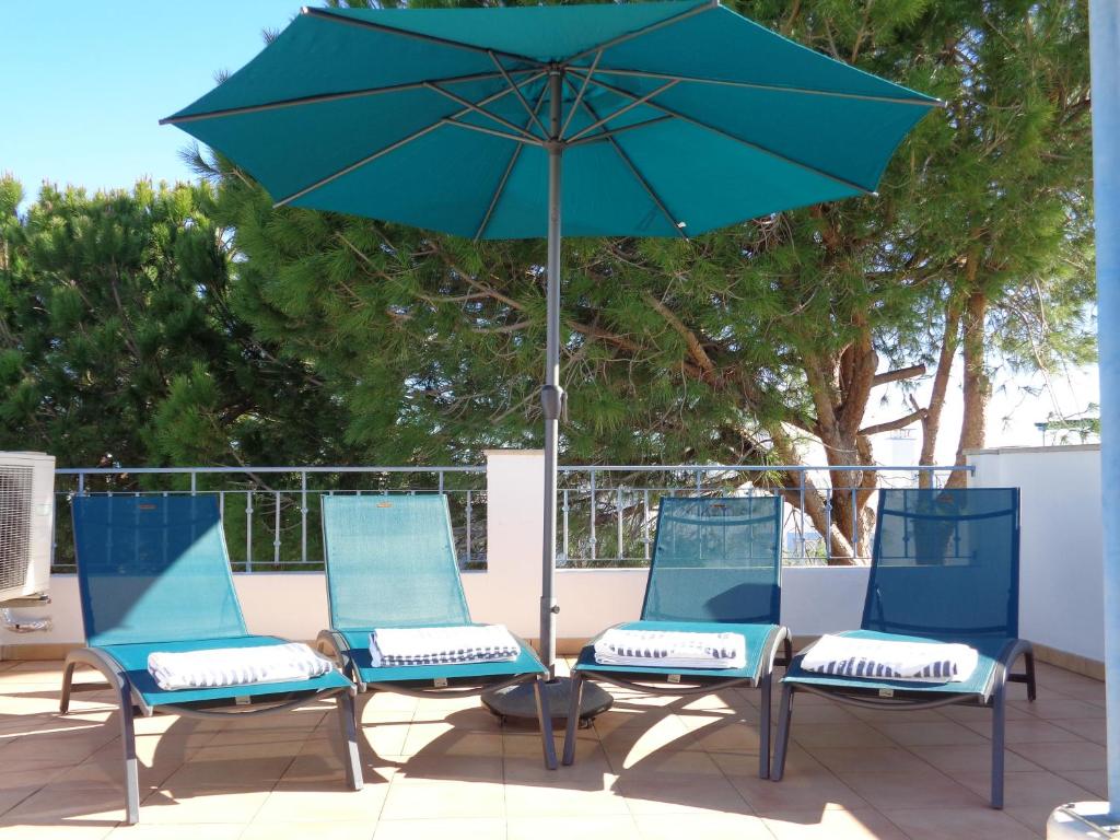 Praia VerdeFarol da Cortesia - Praia Verde的庭院里配有三把椅子和一把遮阳伞