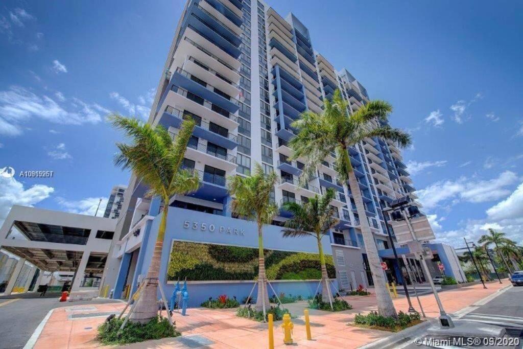 迈阿密APARTMENT FOR RENT 2 BED 2 BATH 1 Parking DOWNTOWN DORAL的一座高大的建筑,前面有棕榈树