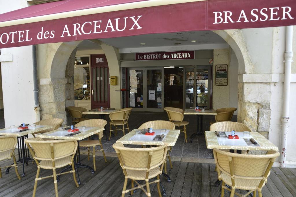 Saint-SeverHôtel Des Arceaux的大楼前设有桌椅的餐厅