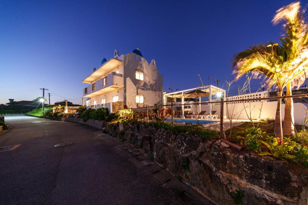 宫古岛Crystal Villa ikema的一座种植了棕榈树和街道的大型白色房屋