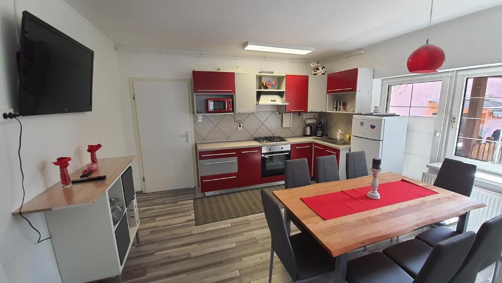 马里博尔Apartma4us的厨房配有红色橱柜和一张带椅子的木桌