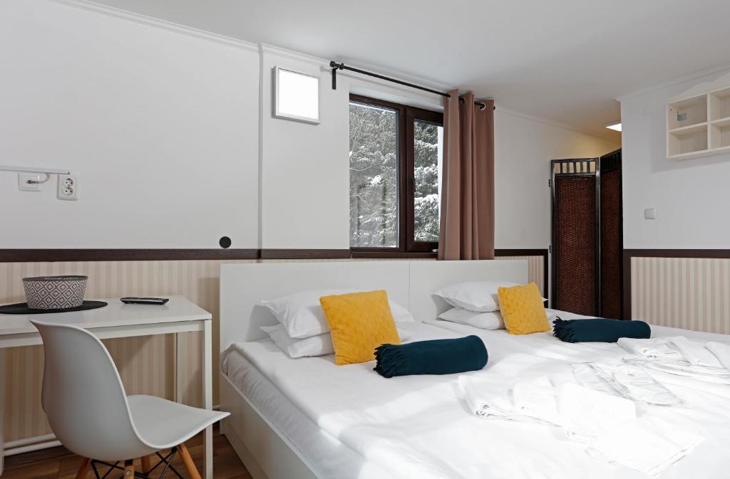 布什泰尼Caraiman Hive的一间卧室配有白色的床和黄色及蓝色枕头