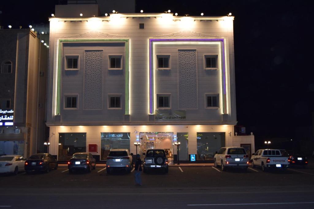 Sīdī Ḩamzahفندق اللؤلؤة الذهبي的停车场内停放汽车的大型建筑