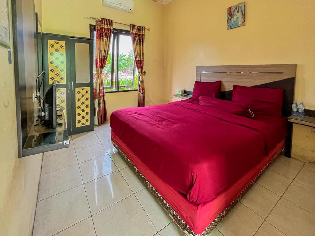 SampitGreenville Hotel Mitra RedDoorz的一间卧室配有一张带红色枕头的大床