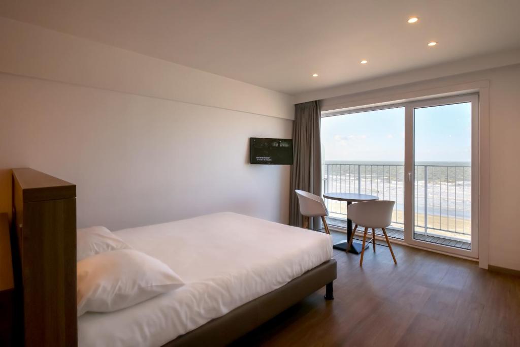 尼乌波特Hotel Sandeshoved Zeedijk的一间卧室配有一张床、一张桌子和一个大窗户