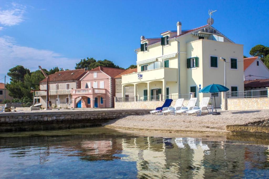 克拉帕尼岛Riva 2的水边的一座建筑,里面摆放着椅子和雨伞