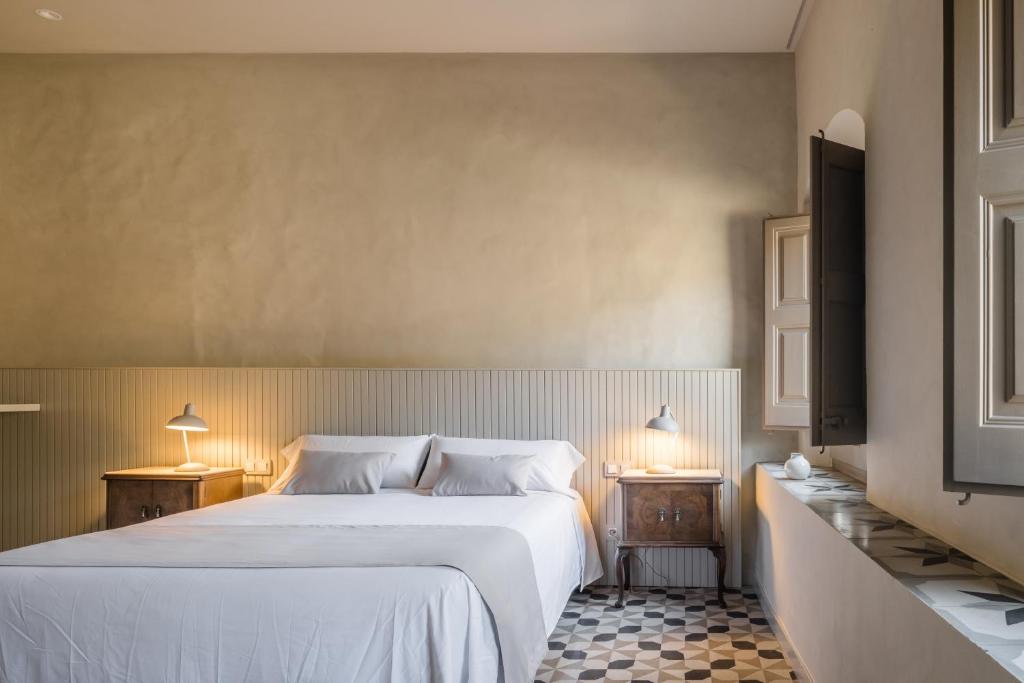 比拉德劳Casa Fàbregas - Benestar Natural的卧室配有一张白色大床和两盏灯。