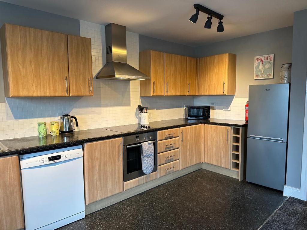 德比Stylish 2 Bed Apartment Derby的厨房配有木制橱柜和白色冰箱。
