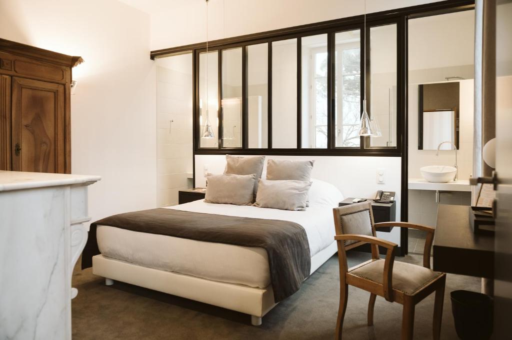 Saint-Sulpice多迈纳恩法戈酒店的一间卧室配有一张床、一张桌子和一把椅子