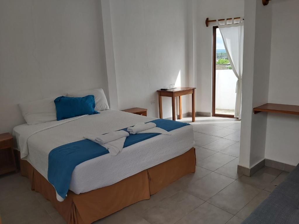 阿约拉港加拉帕戈斯原住民旅馆的一间卧室配有一张带蓝白色床单的大床