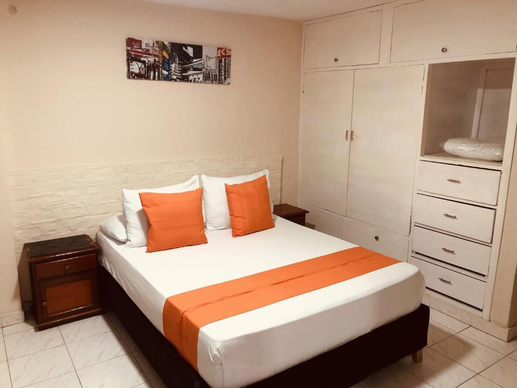 巴兰基亚Hotel Boston Superior的一间卧室配有一张带橙色枕头的大床
