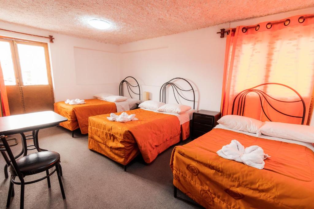 阿亚库乔Hotel San Francisco de Paula Ayacucho的一间设有三张床的房间,内设一张桌子