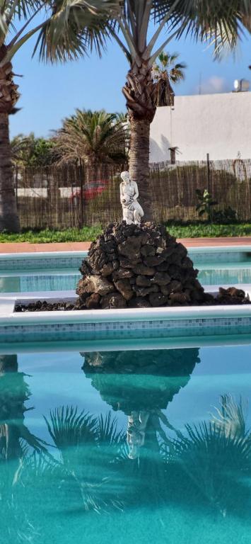 查德尔帕罗奥Villa Harmony的棕榈树泳池中间的雕像