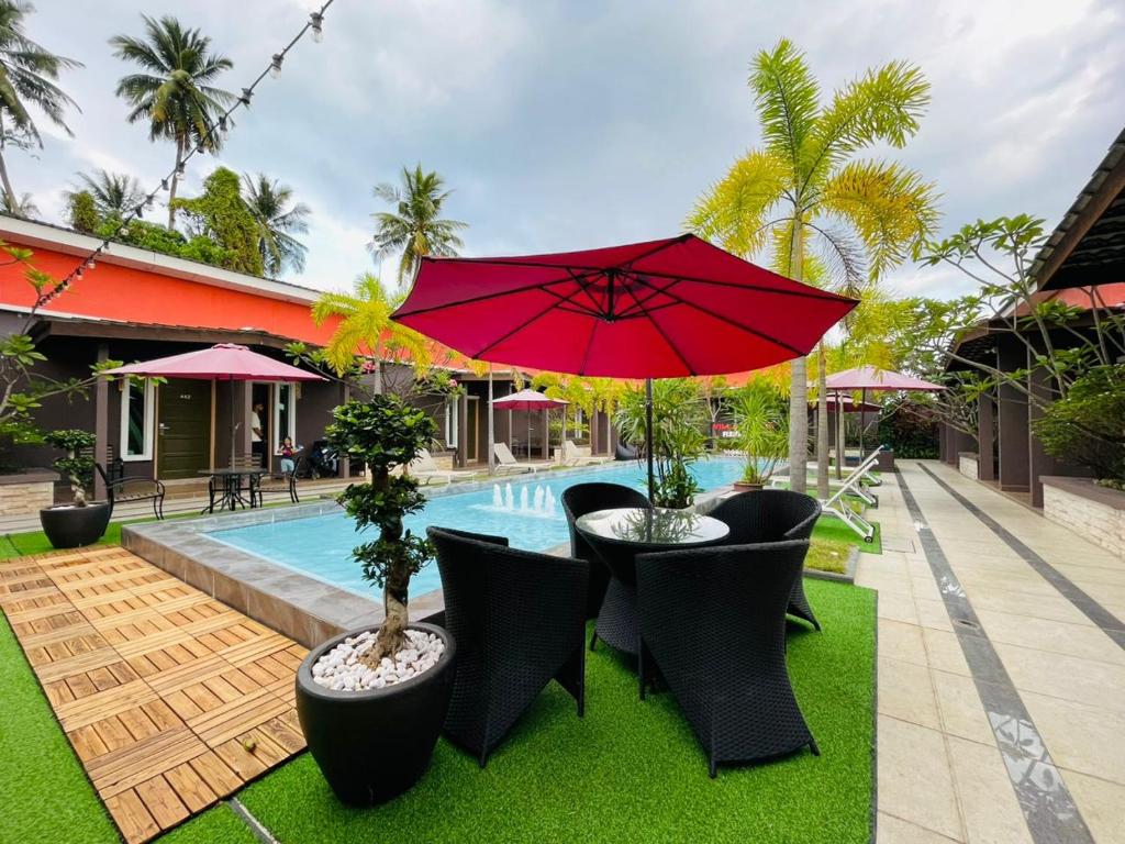 珍南海滩阿巴迪别墅度假酒店的一个带红色遮阳伞和椅子的庭院和一个游泳池
