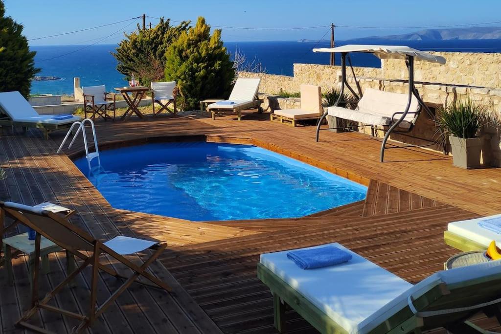 卡特罗斯Pamela's house "private pool and spa"的一个带椅子和遮阳伞的木制甲板上的游泳池