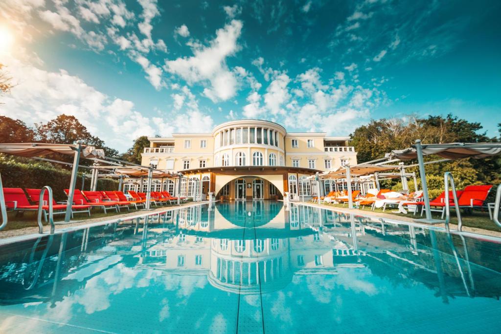 基尔绍Hotel BEI SCHUMANN的度假村的游泳池,配有红白遮阳伞