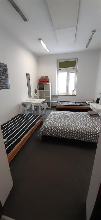 克拉科夫Master Corner Apartment的客房设有两张床、一张桌子和一扇窗户。