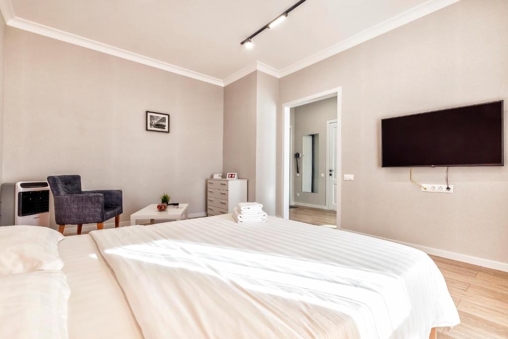 阿斯塔纳Raisson Ahotel T91的白色卧室设有一张大床和一台平面电视。
