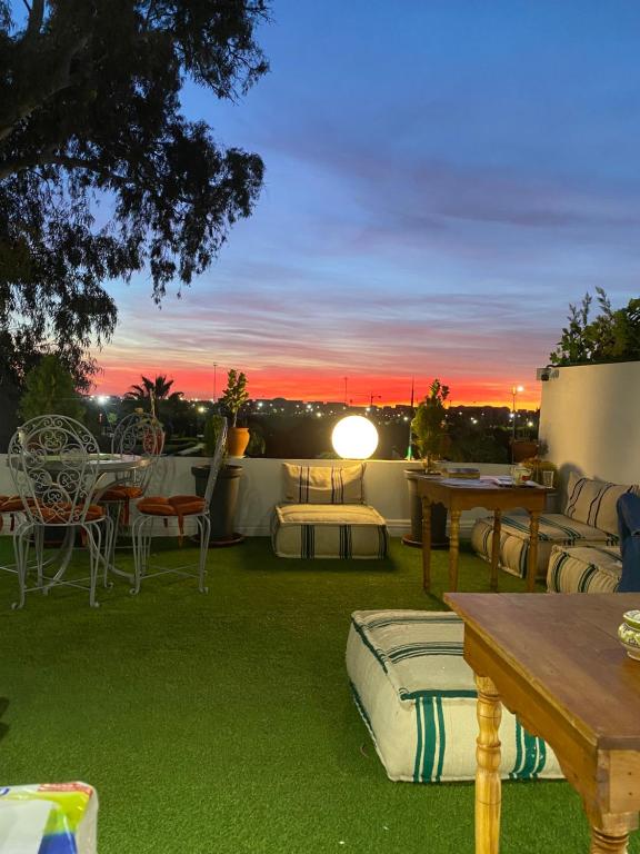 马拉喀什Winarouze house的一个带桌椅的庭院,享有日落美景。