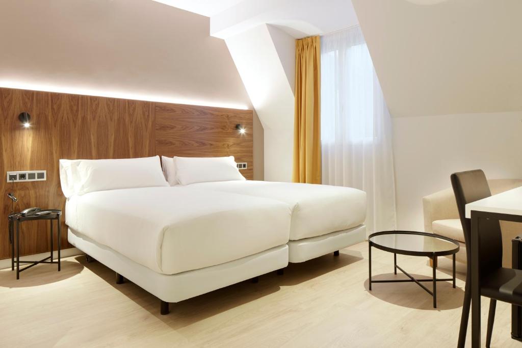 圣塞瓦斯蒂安阿里祖尔国会酒店的卧室配有一张白色的大床和一张桌子
