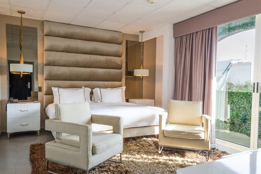 雷诺萨Hotel Posada San Antonio的卧室配有白色的床和2把椅子