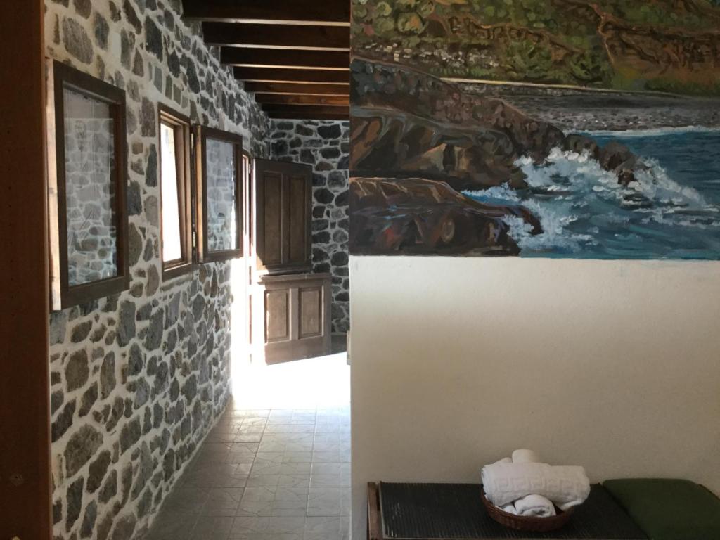 MandrákionVolcano View Nisyros的走廊上墙上有画作和桌子