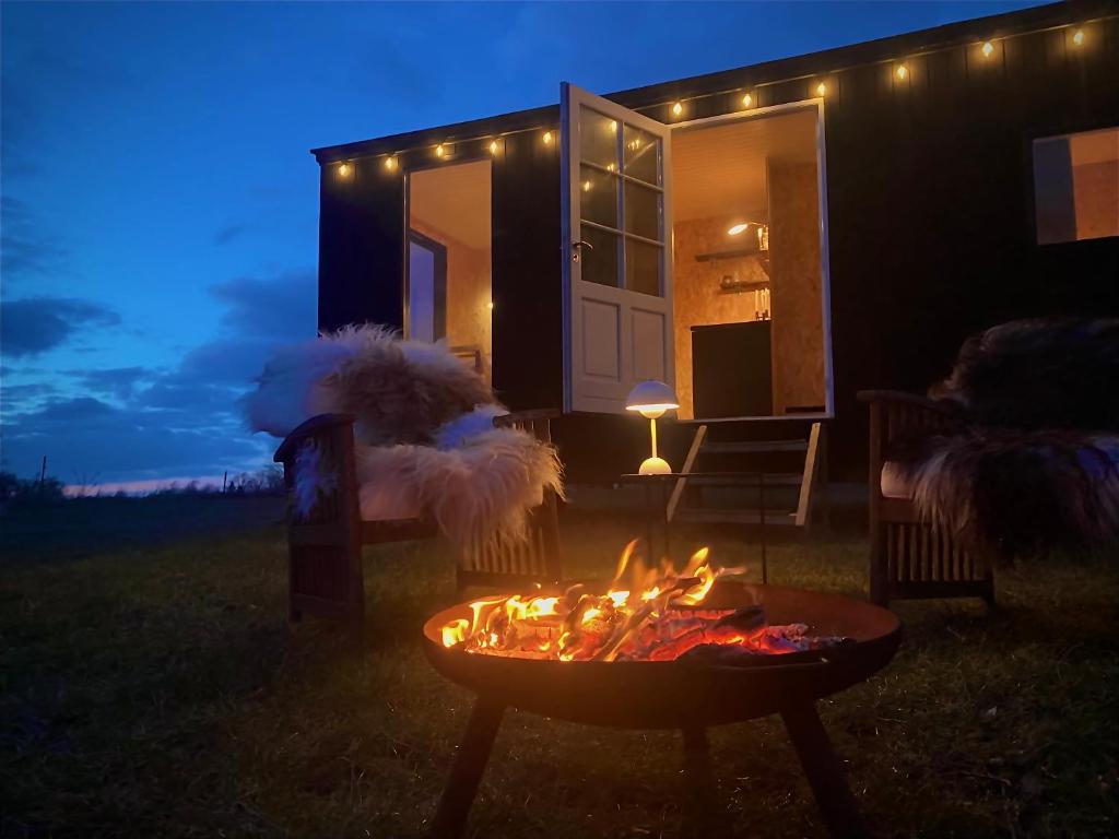 SkibbyCozy Tiny House on a farm的夜晚在房子前面的火坑